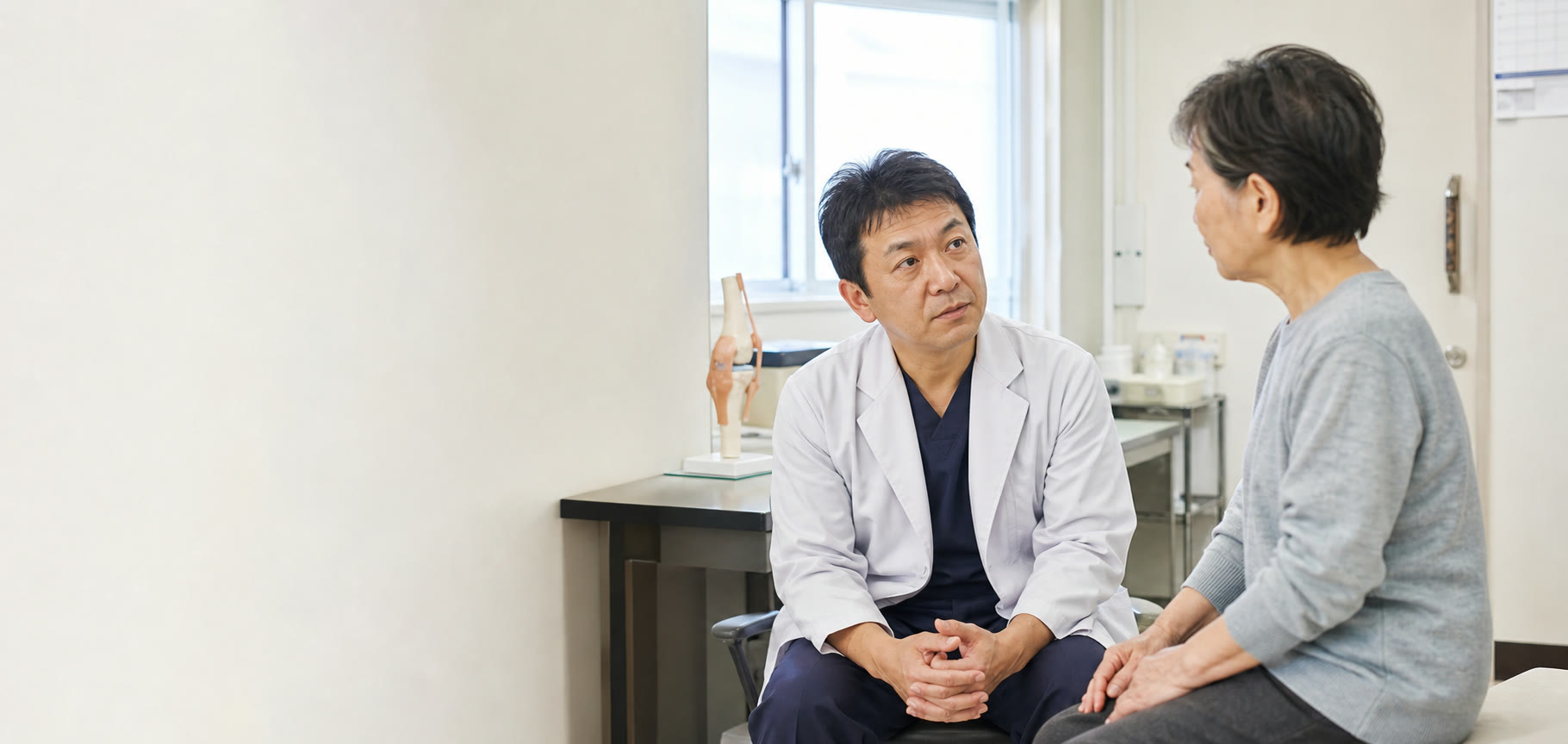 診察室で患者の話を聞く医師